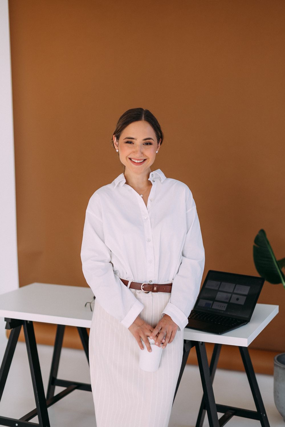 Viktorija Garanca standing at a desk with a laptop, smiling