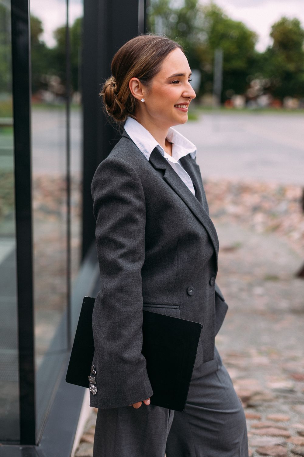 Viktorija Garanca in a grey blazer, laptop under her arm, smiling in profile