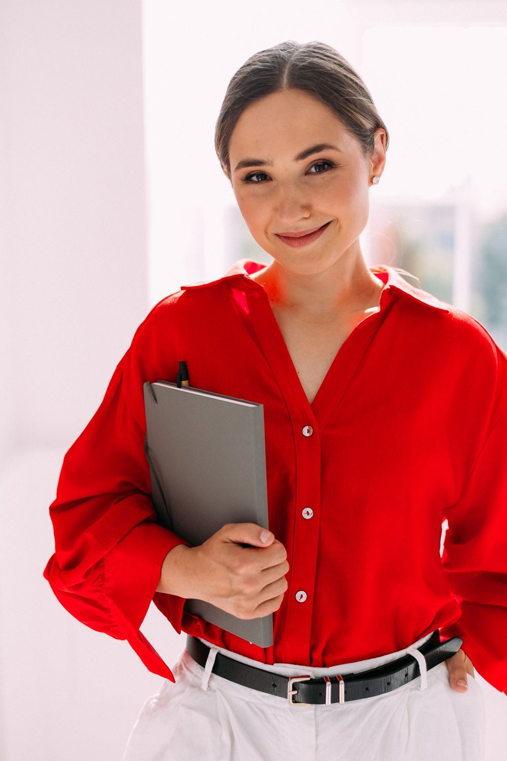 Viktorija Garanca in a red blouse, smiling, holding a notebook